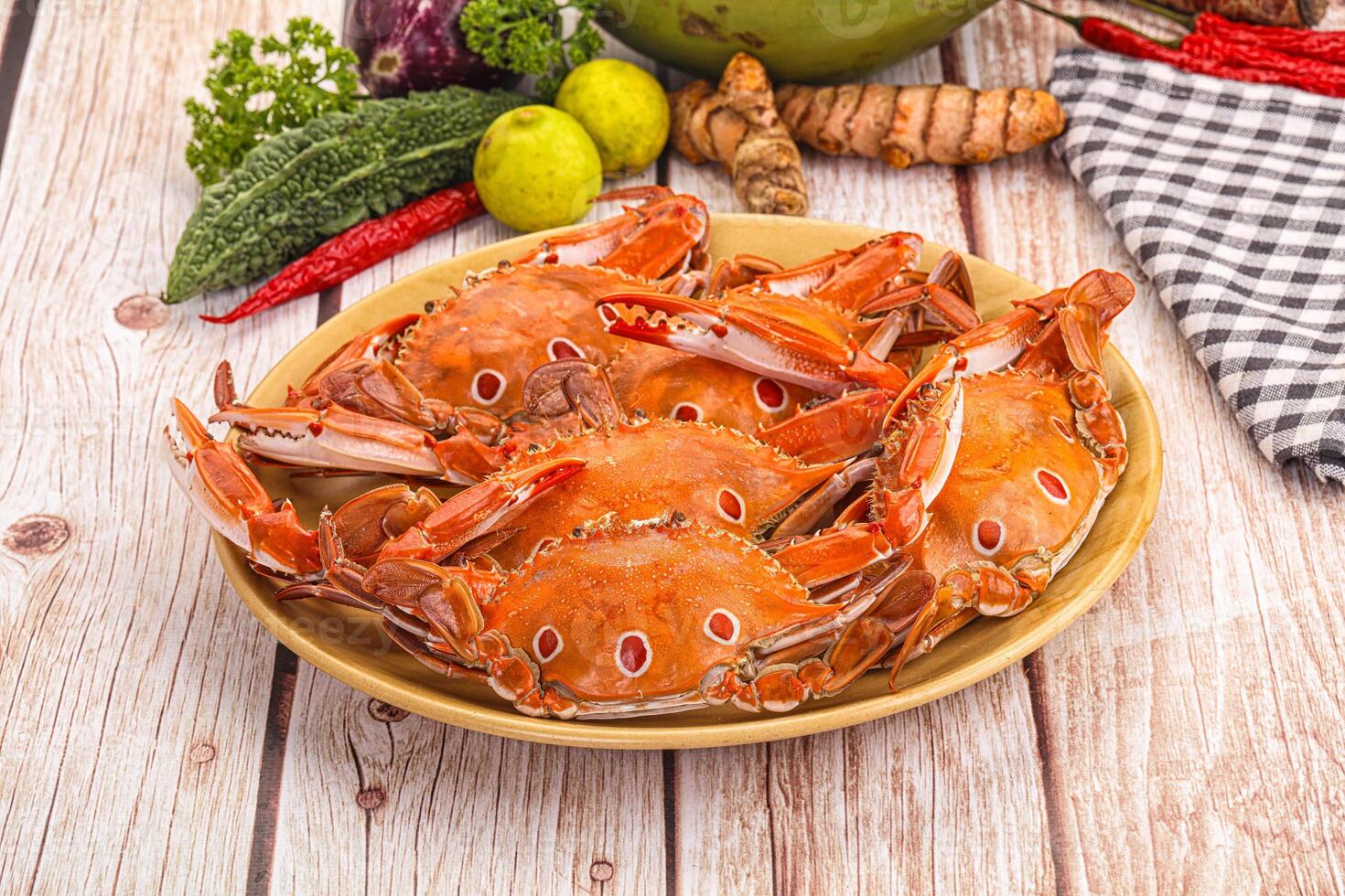 A plate of crabs on a table with other vegetables photo