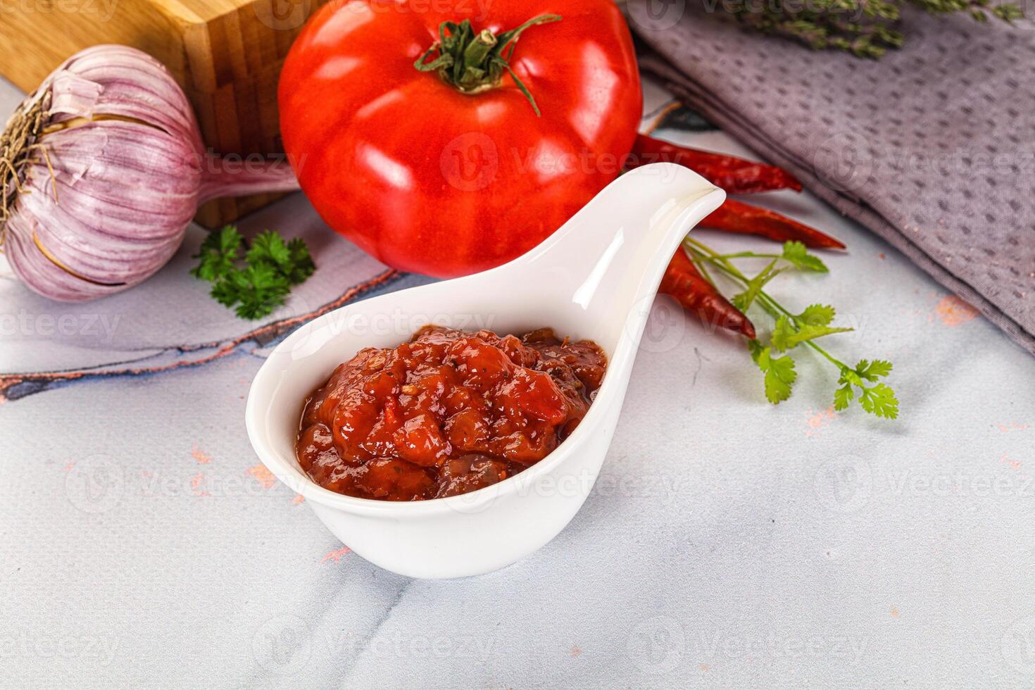 A white spoon with a tomato and garlic on it photo