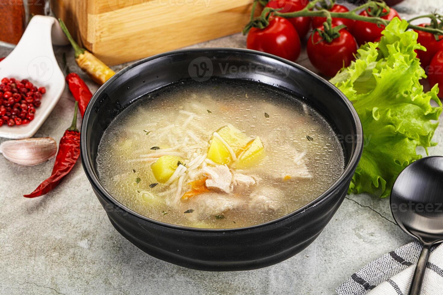 A bowl of soup with vegetables and herbs photo