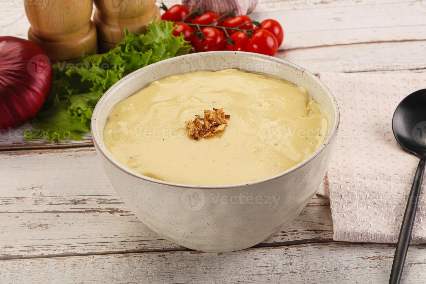 A bowl of soup with a spoon and some vegetables photo
