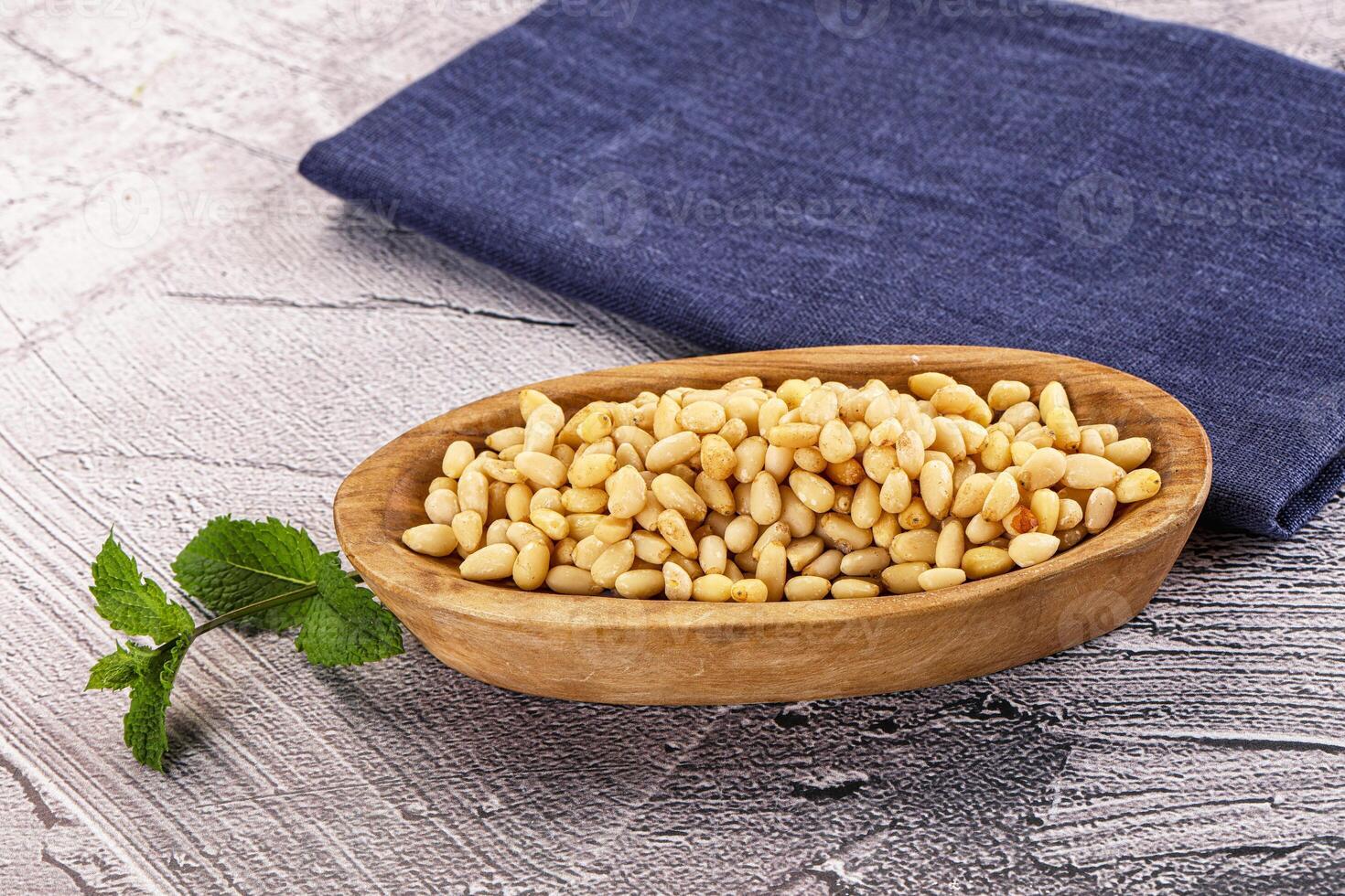 A wooden bowl with a spoon of nuts and a napkin photo