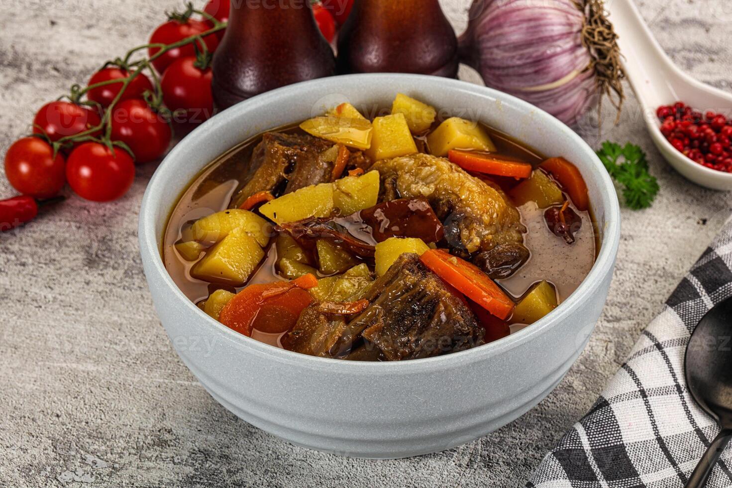 A bowl of stew with vegetables and meat on a table photo