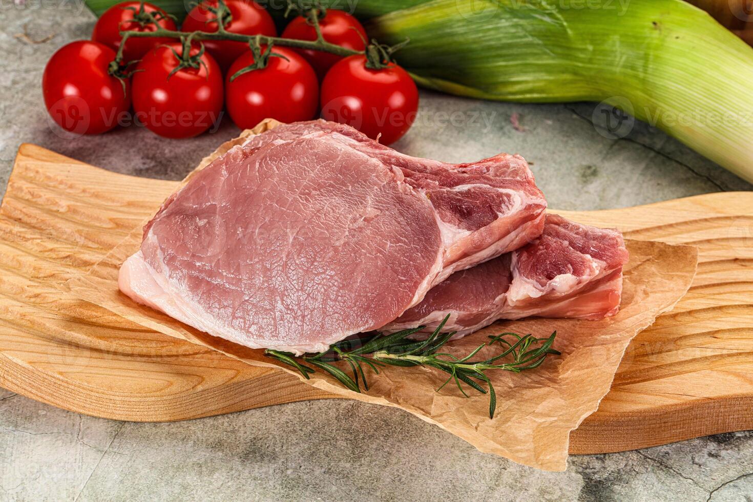 Raw pork on a cutting board with vegetables photo