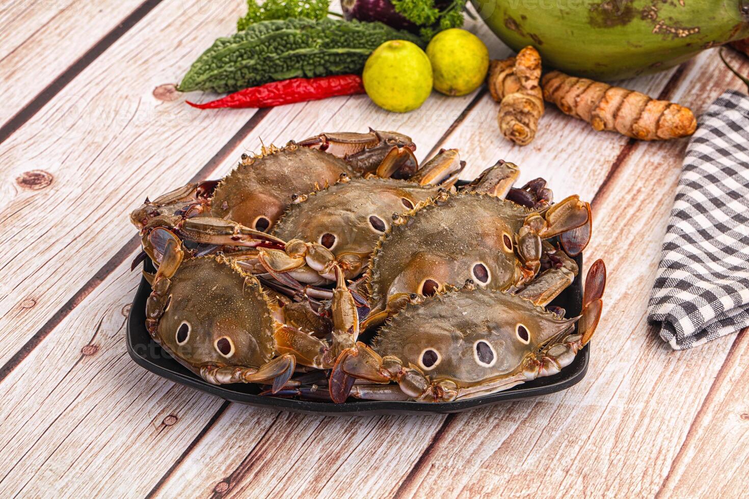 A plate of crabs on a table with a bowl of vegetables photo