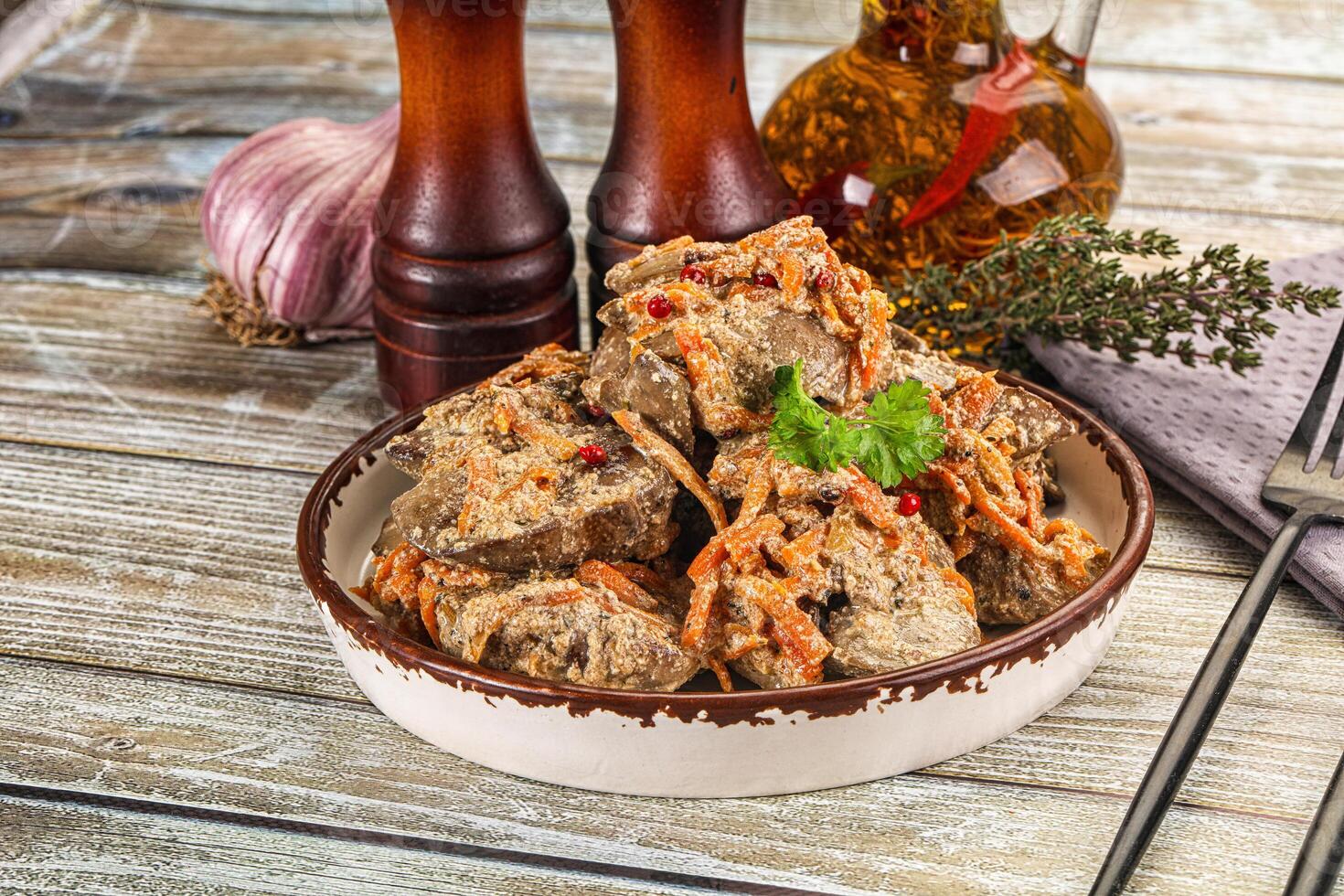 A bowl of meat with vegetables on a wooden table photo