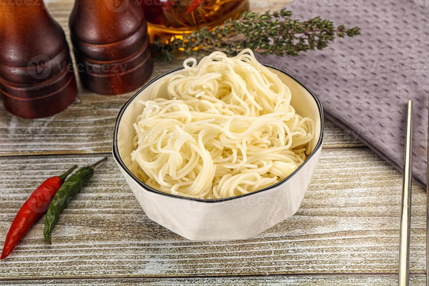 Chopsticks and noodles in a bowl on a wooden table photo