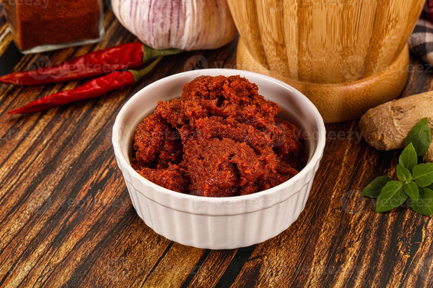 A bowl of chili powder next to a pepper grinder photo