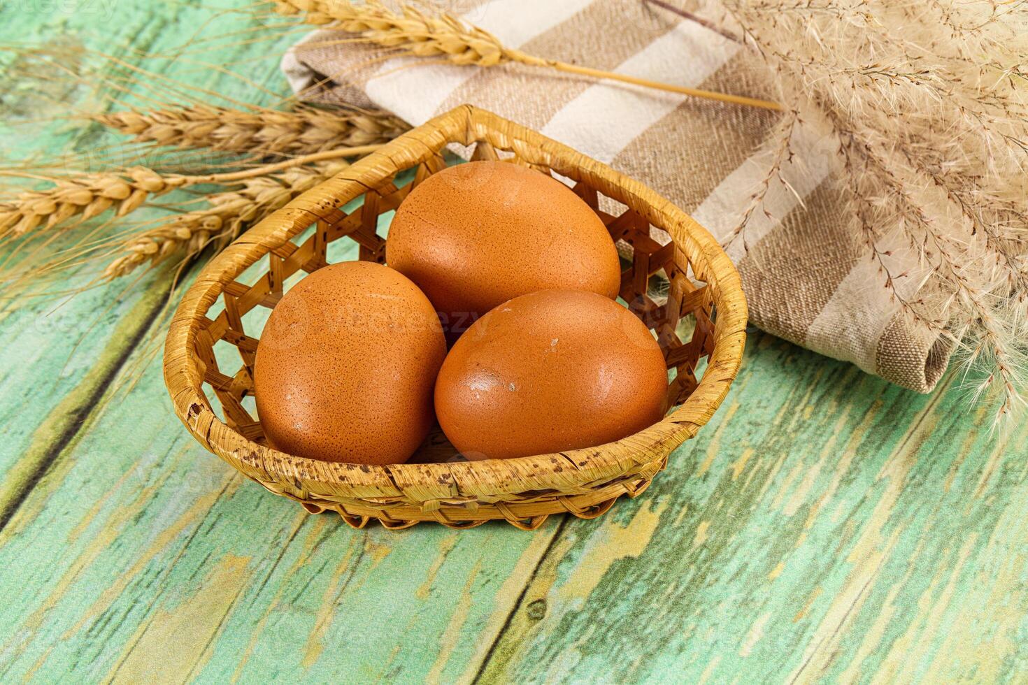 Three eggs in a basket on a wooden table photo