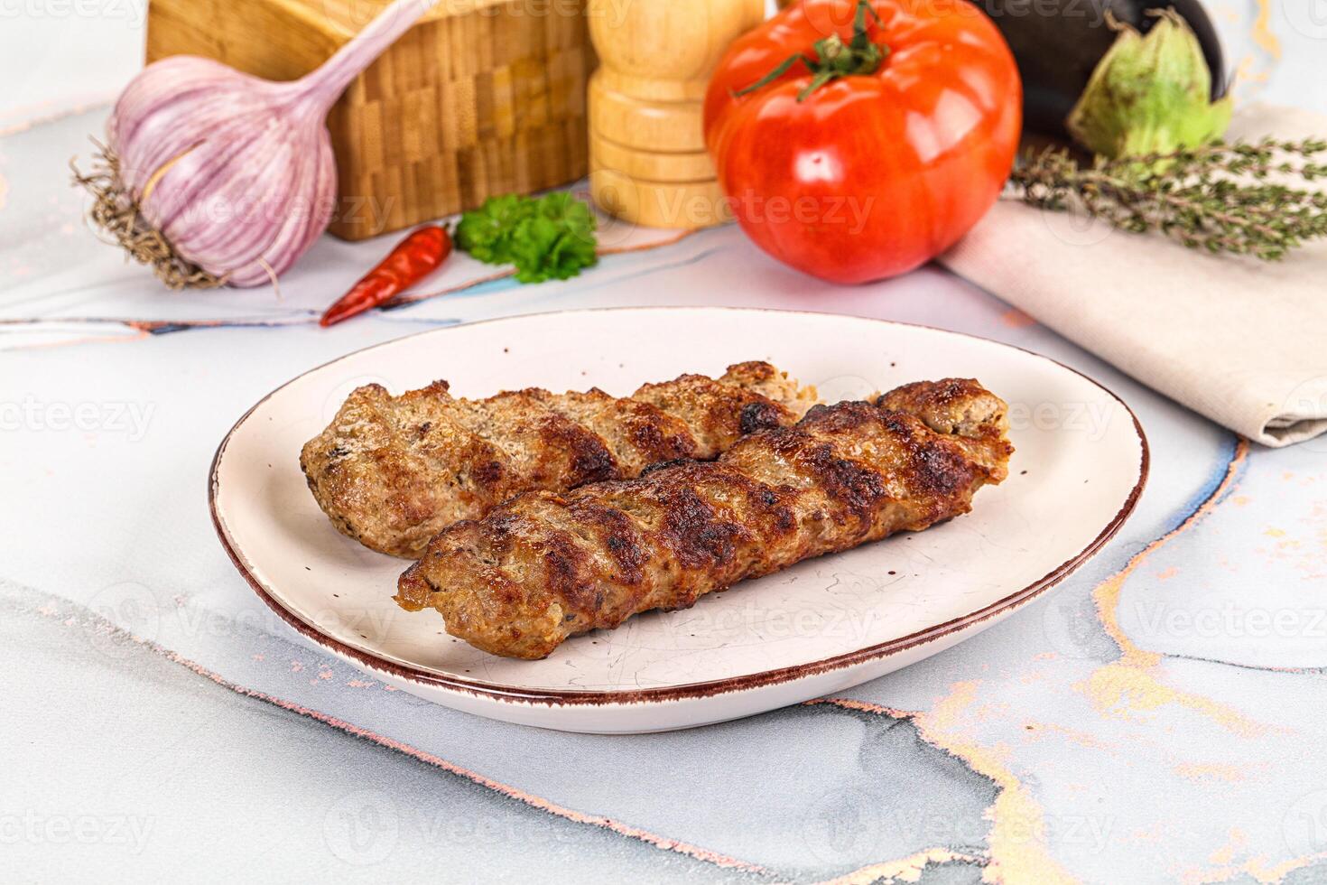 Two meat skewers on a white plate with vegetables photo