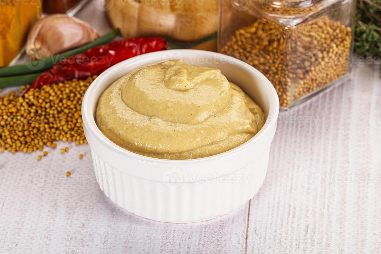 A bowl of mustard and spices on a table photo