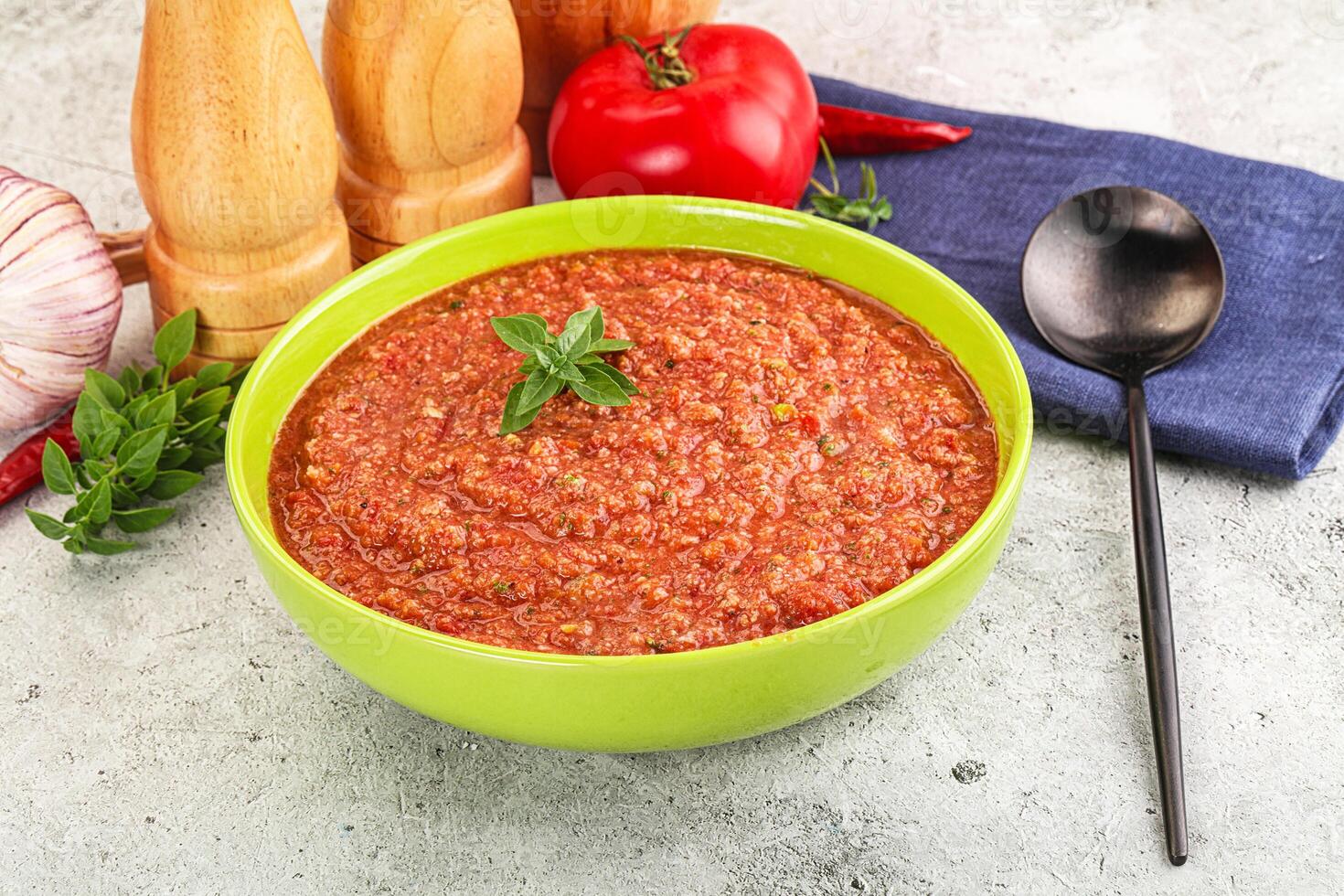 A bowl of tomato sauce with a spoon and a knife photo