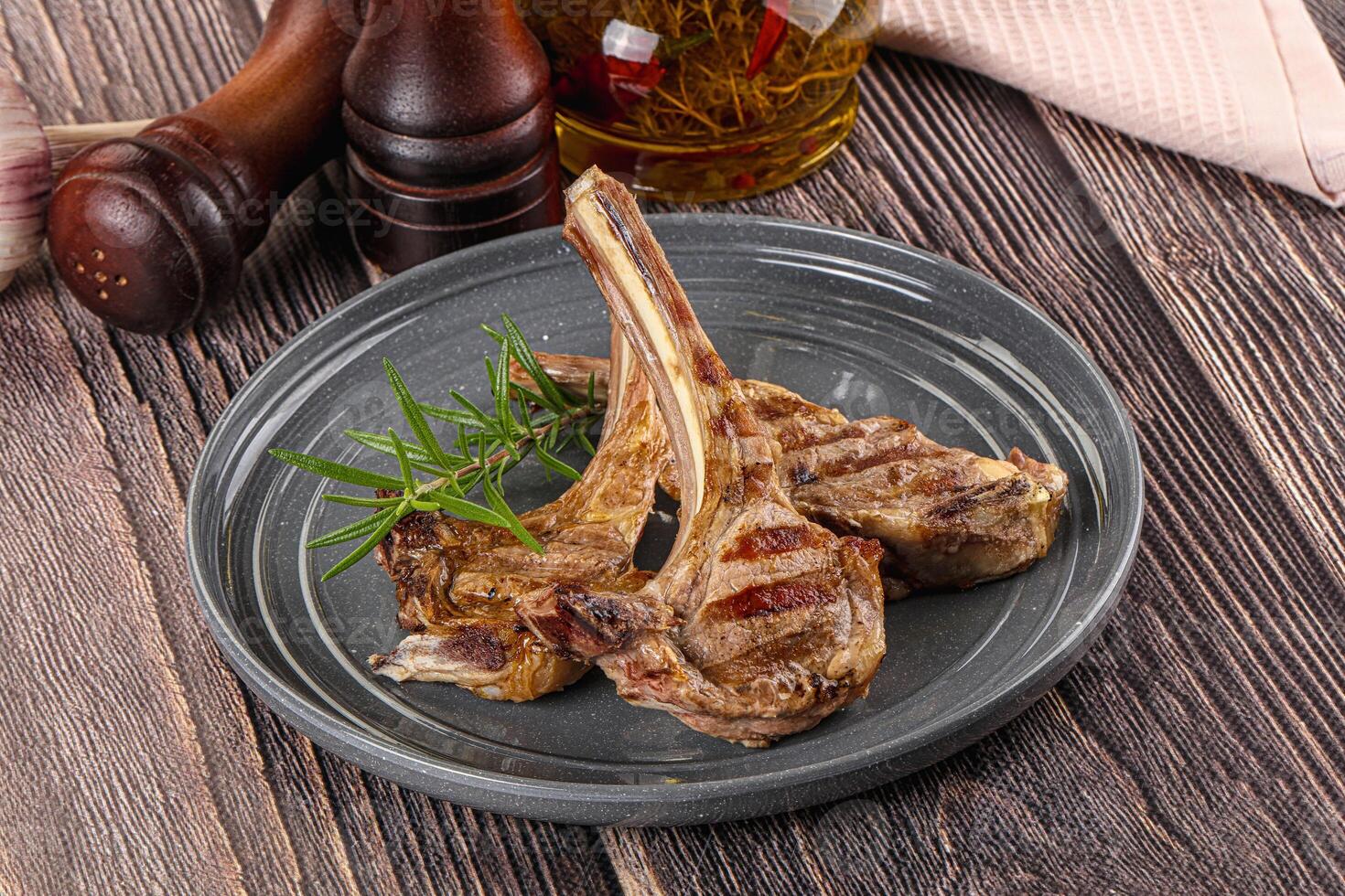 Grilled lamb chops on a plate on a wooden table photo