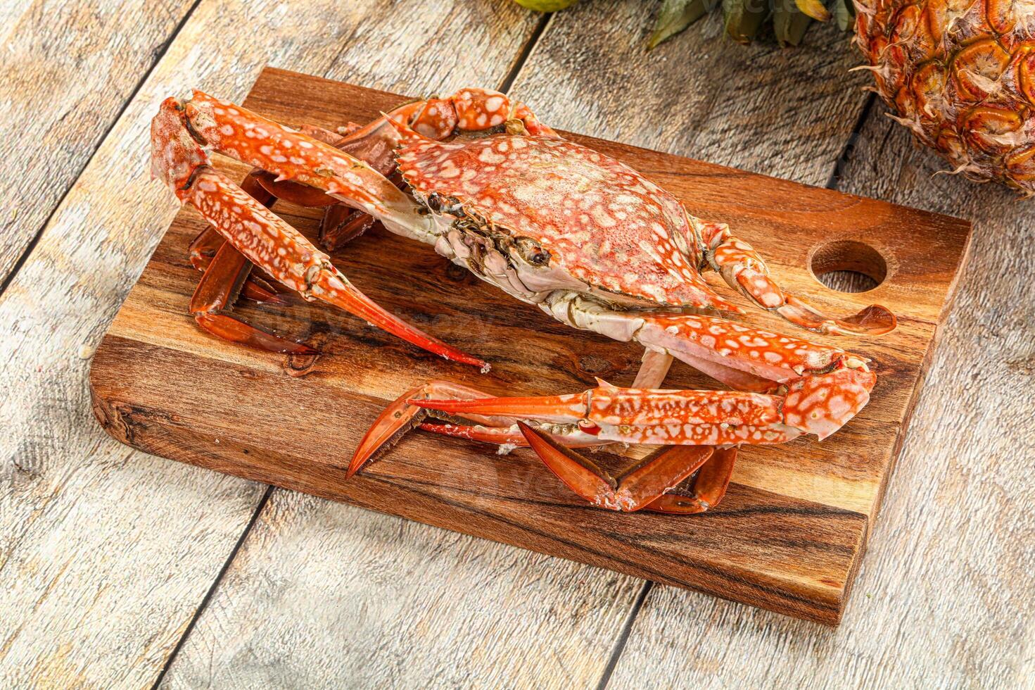 A crab on a cutting board with pineapples and a pineapple photo