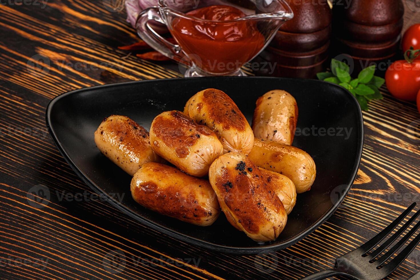A black plate with some sausages and ketchup photo