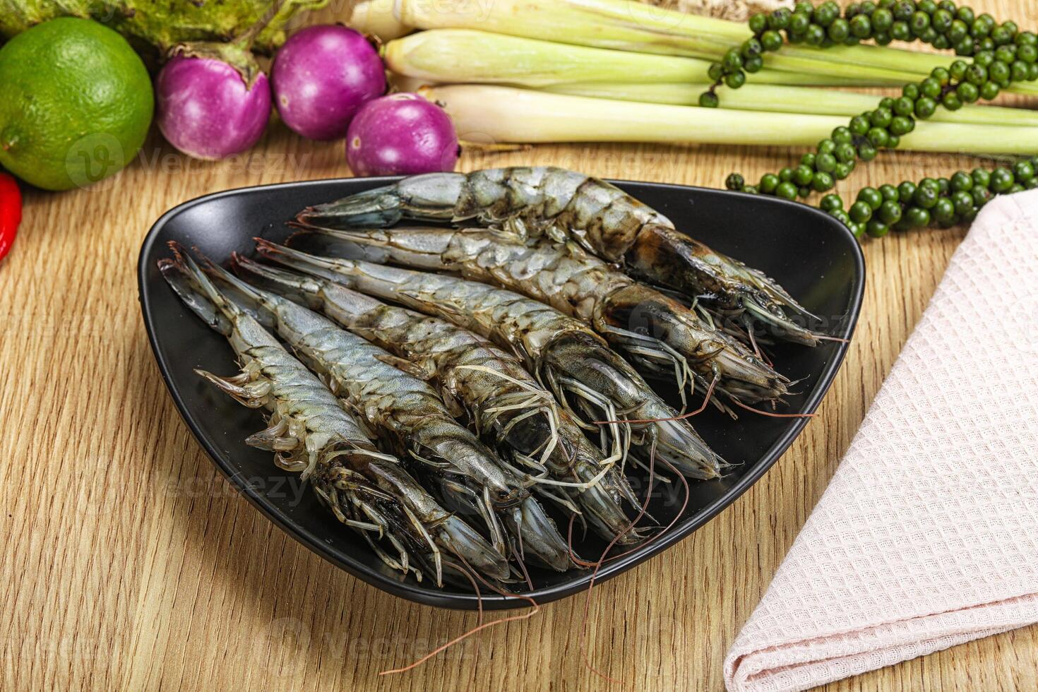 A bowl of cooked shrimp on a table with other vegetables photo
