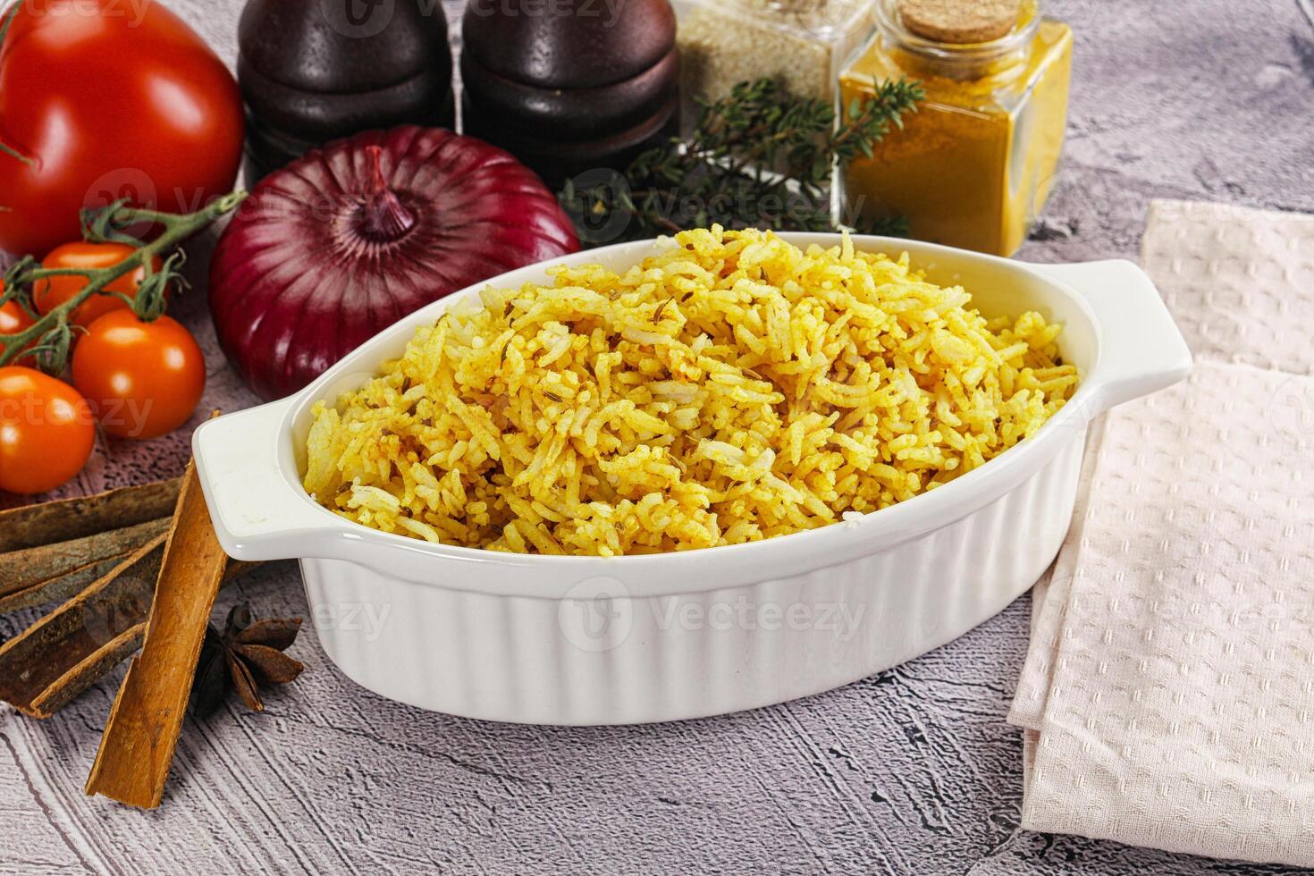 A bowl of rice with spices and vegetables on a table photo