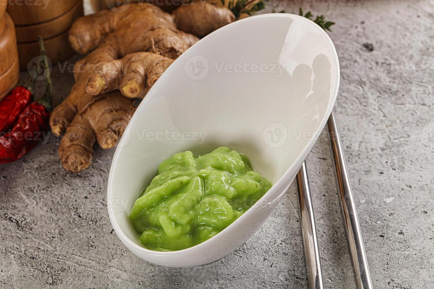 A bowl of green sauce next to a bowl of ginger photo