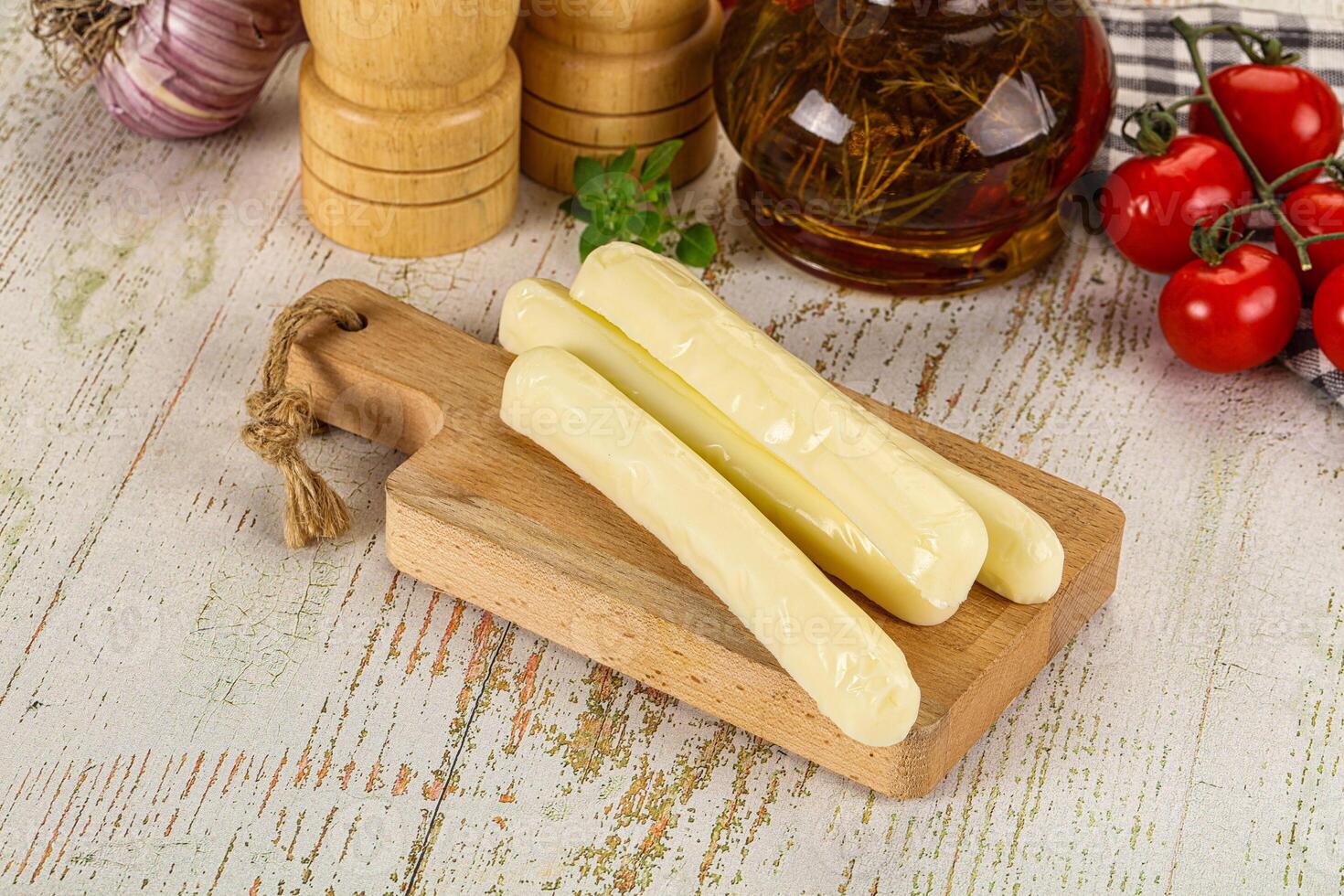 A wooden cutting board with cheese and other ingredients photo
