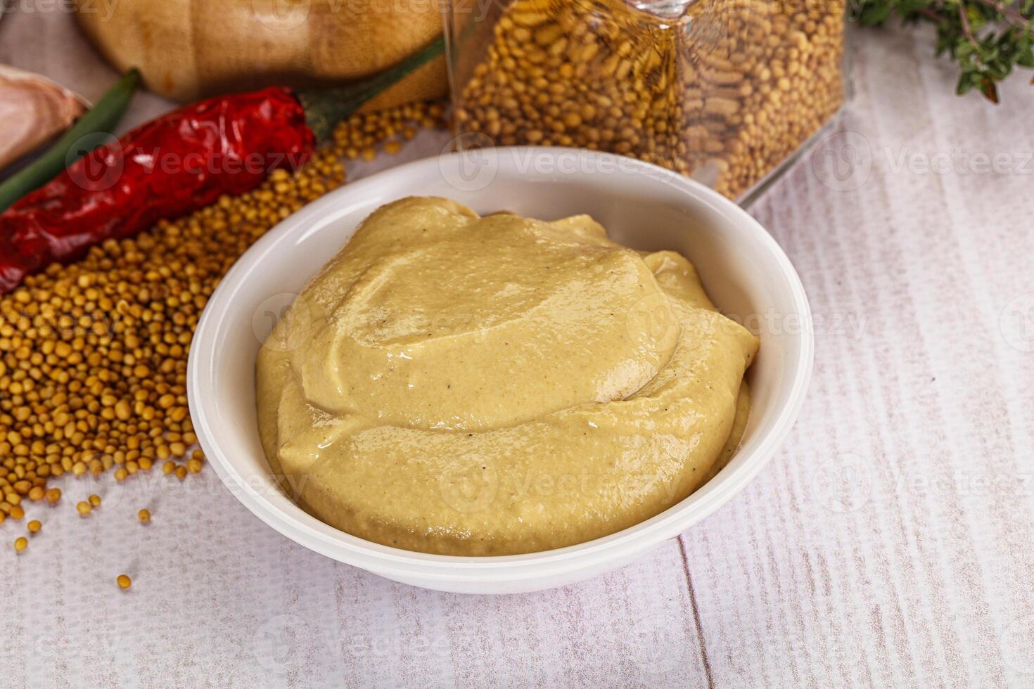 A bowl of mustard next to a bowl of spices photo