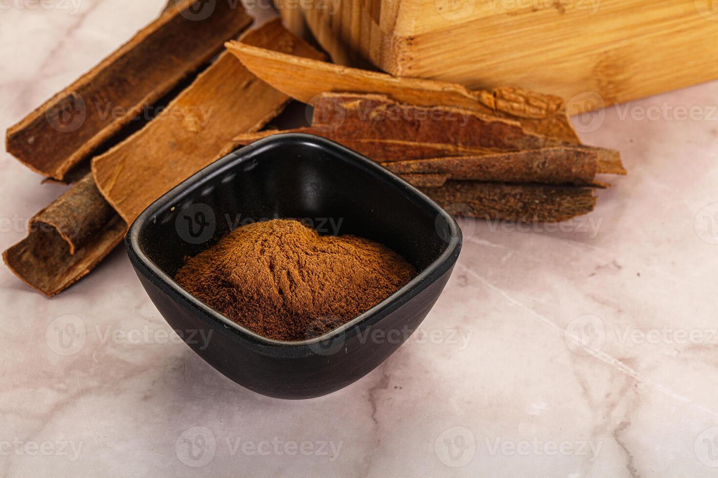 Cinnamon powder in a black cup on a marble surface photo
