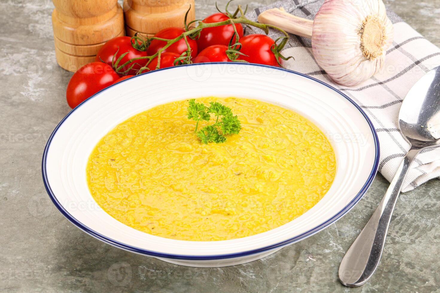 A bowl of soup with a spoon and a knife photo