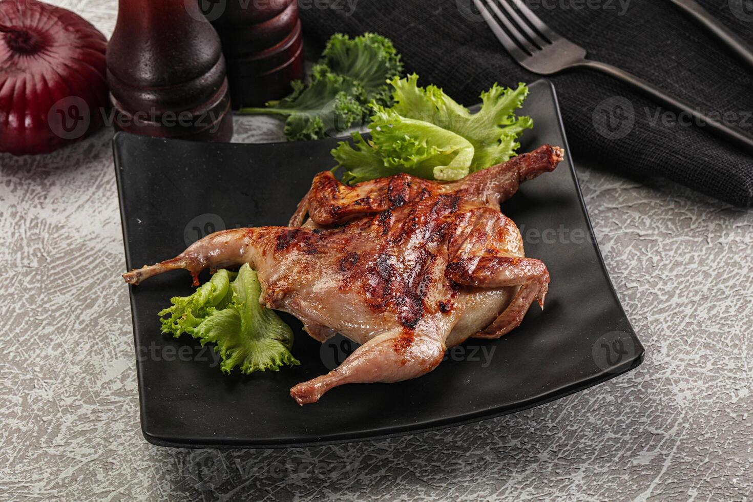 A chicken on a black plate with lettuce and onions photo