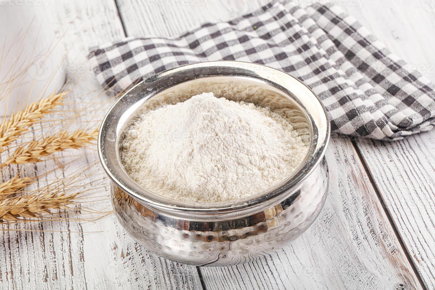 A bowl of flour next to a glass of milk photo