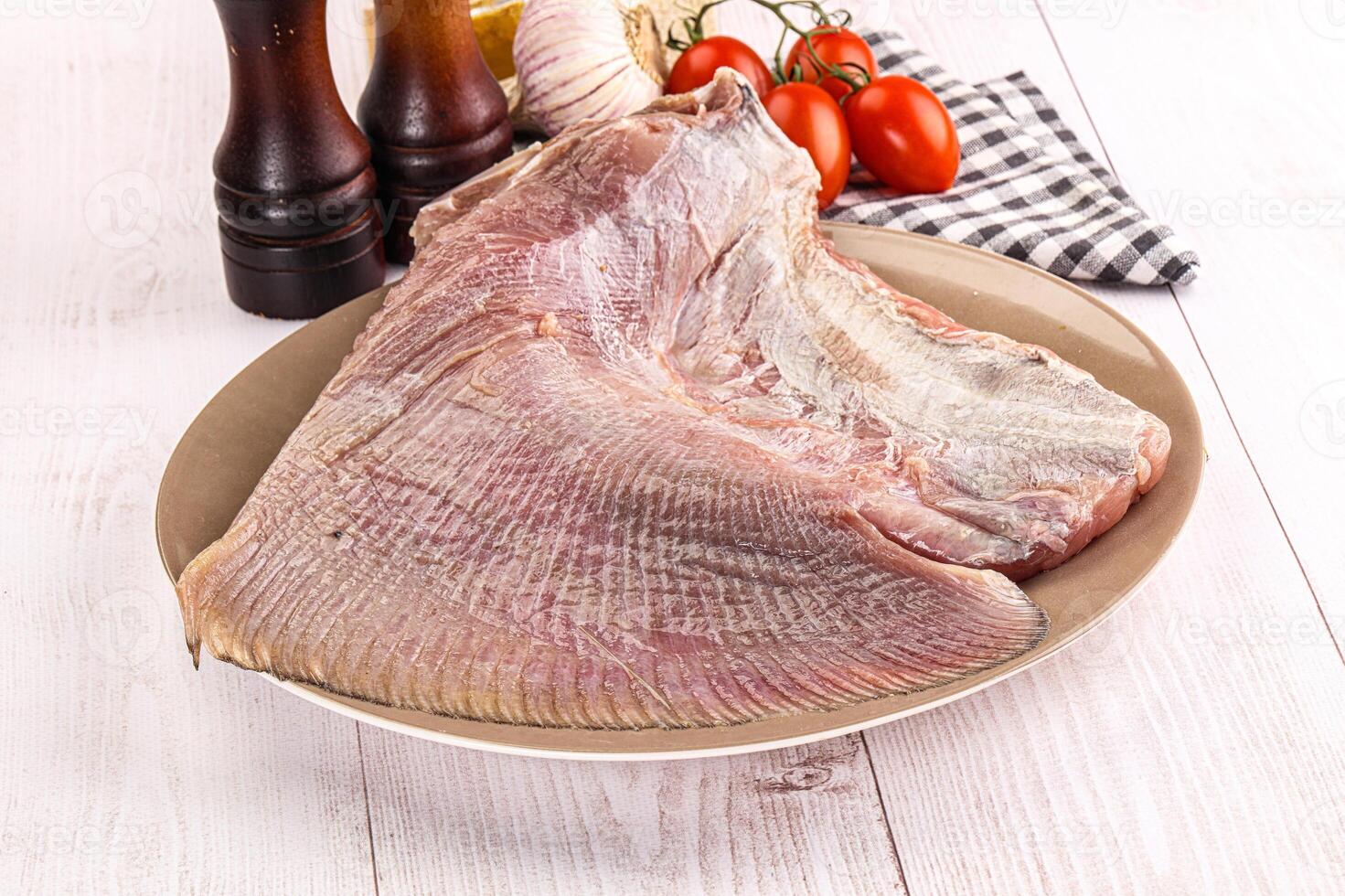A piece of raw fish on a plate with a knife and pepper photo