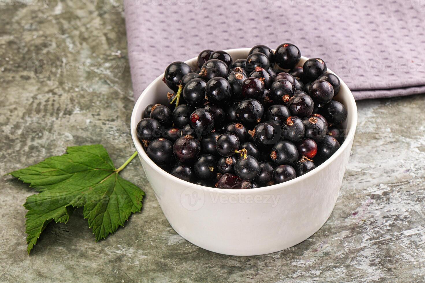 A bowl of black currants on a table photo