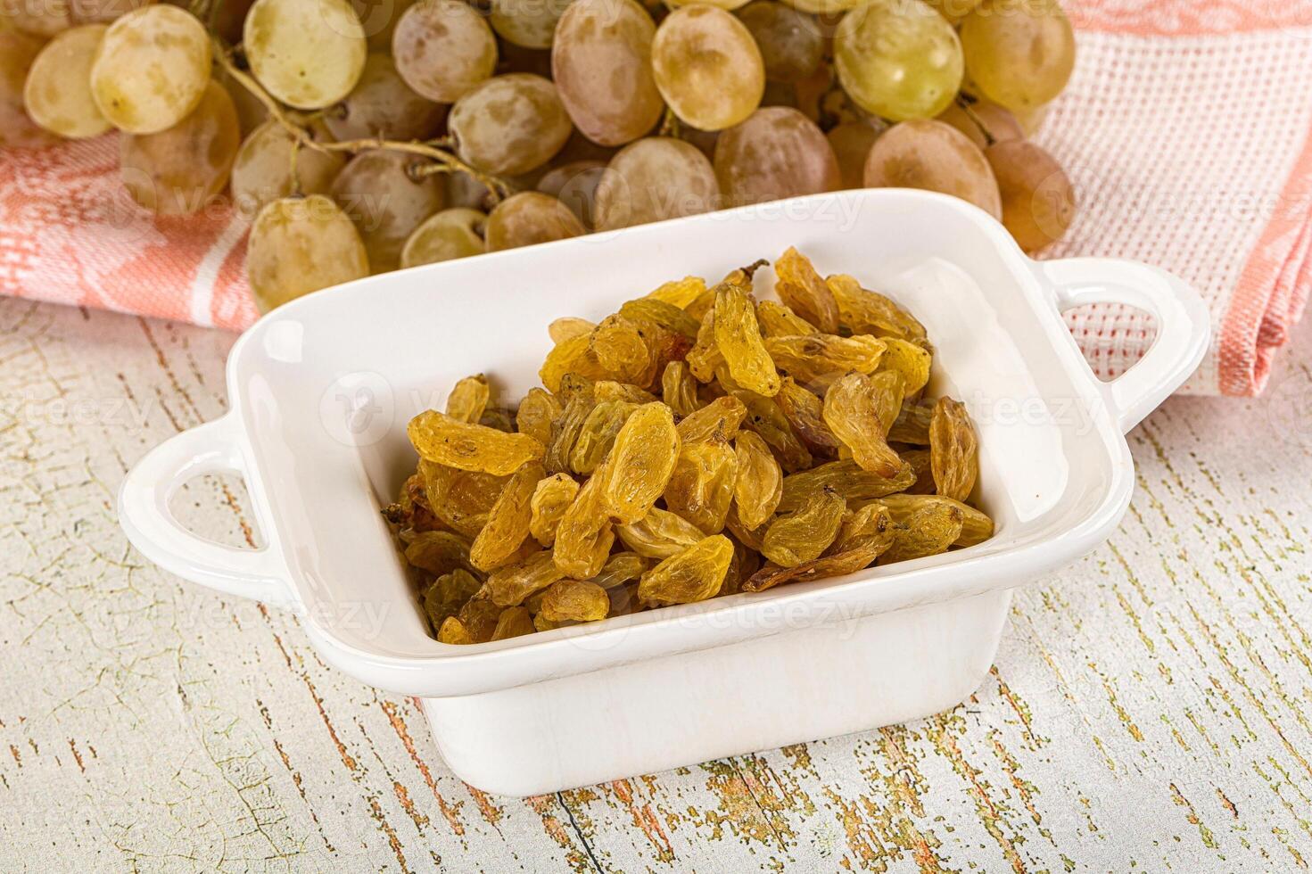 A bowl of raisins and a bowl of grapes photo