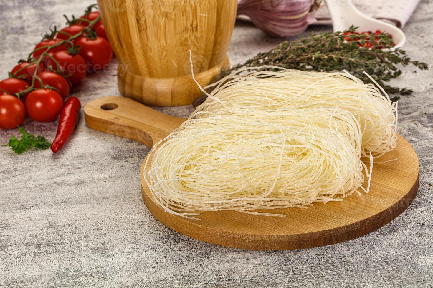 A wooden cutting board with noodles and vegetables photo