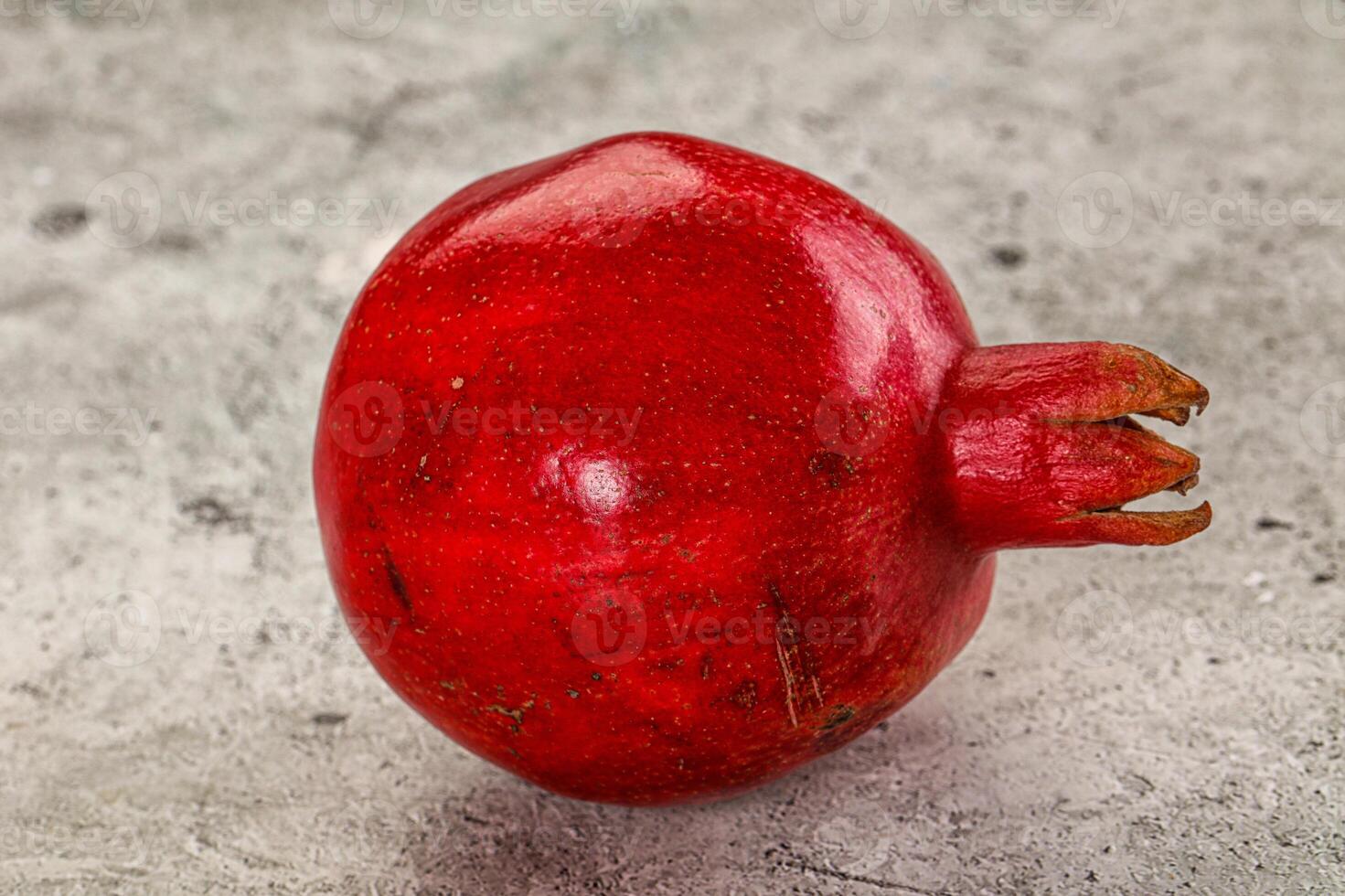 A red pomegranate on a gray surface photo