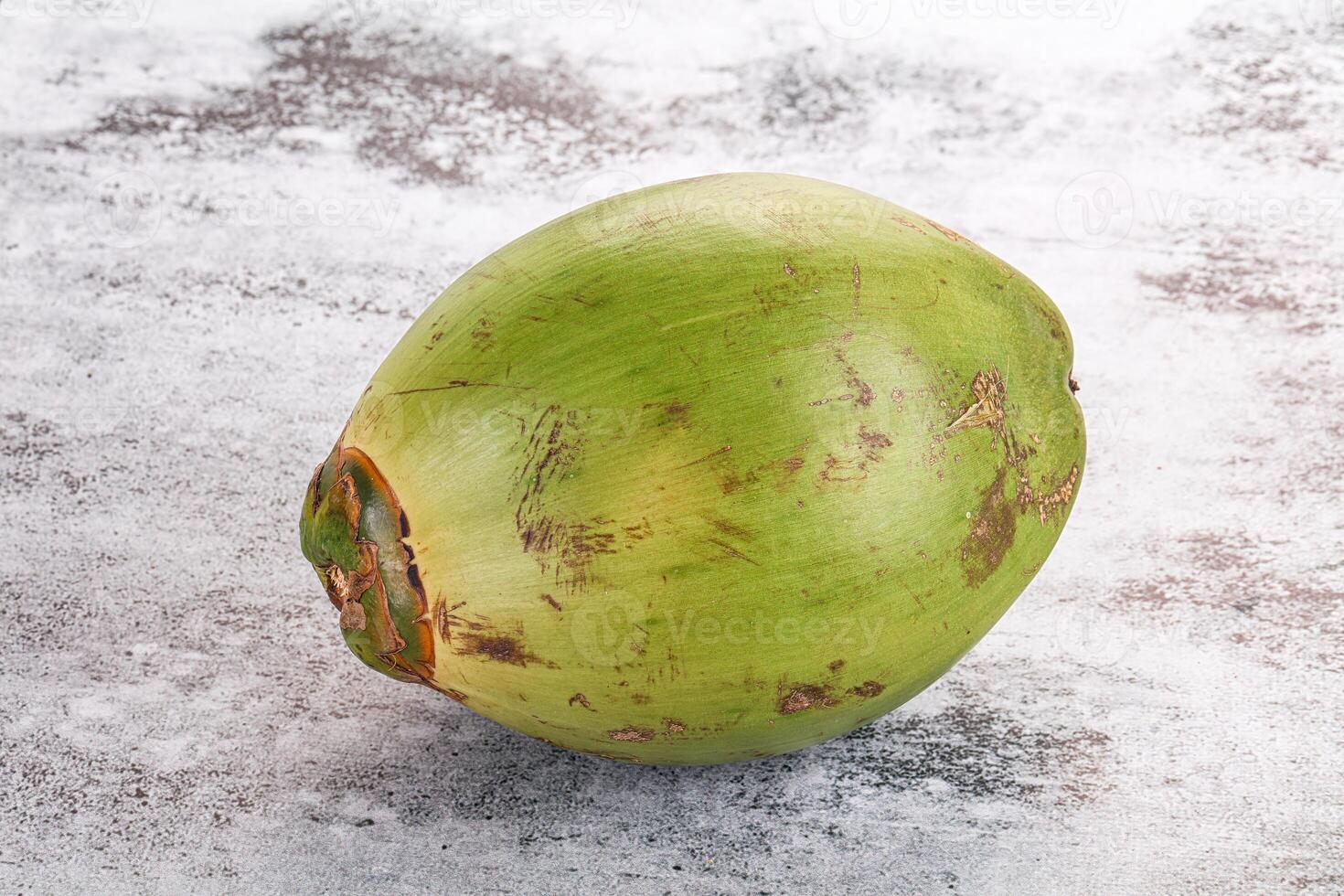 A green coconut on a white surface photo