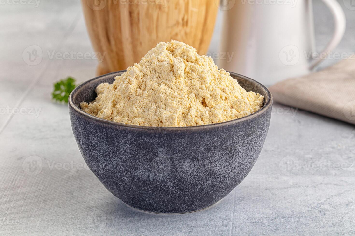 A bowl of flour next to a cup of milk photo