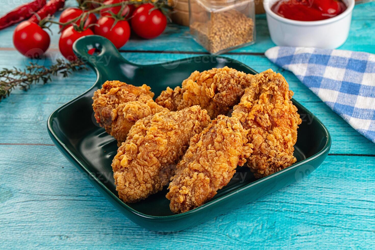 A plate of fried chicken on a table with a bottle of ketchup photo