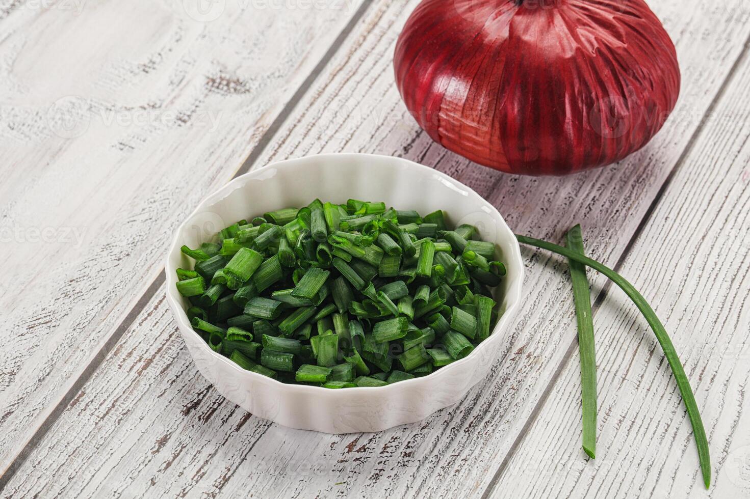 A bowl of chopped green onions and a red onion photo