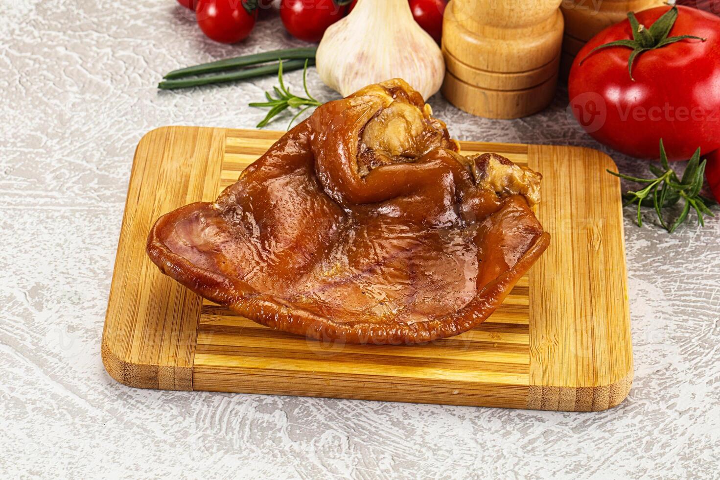 A piece of meat on a cutting board with a knife and a bunch of vegetables photo