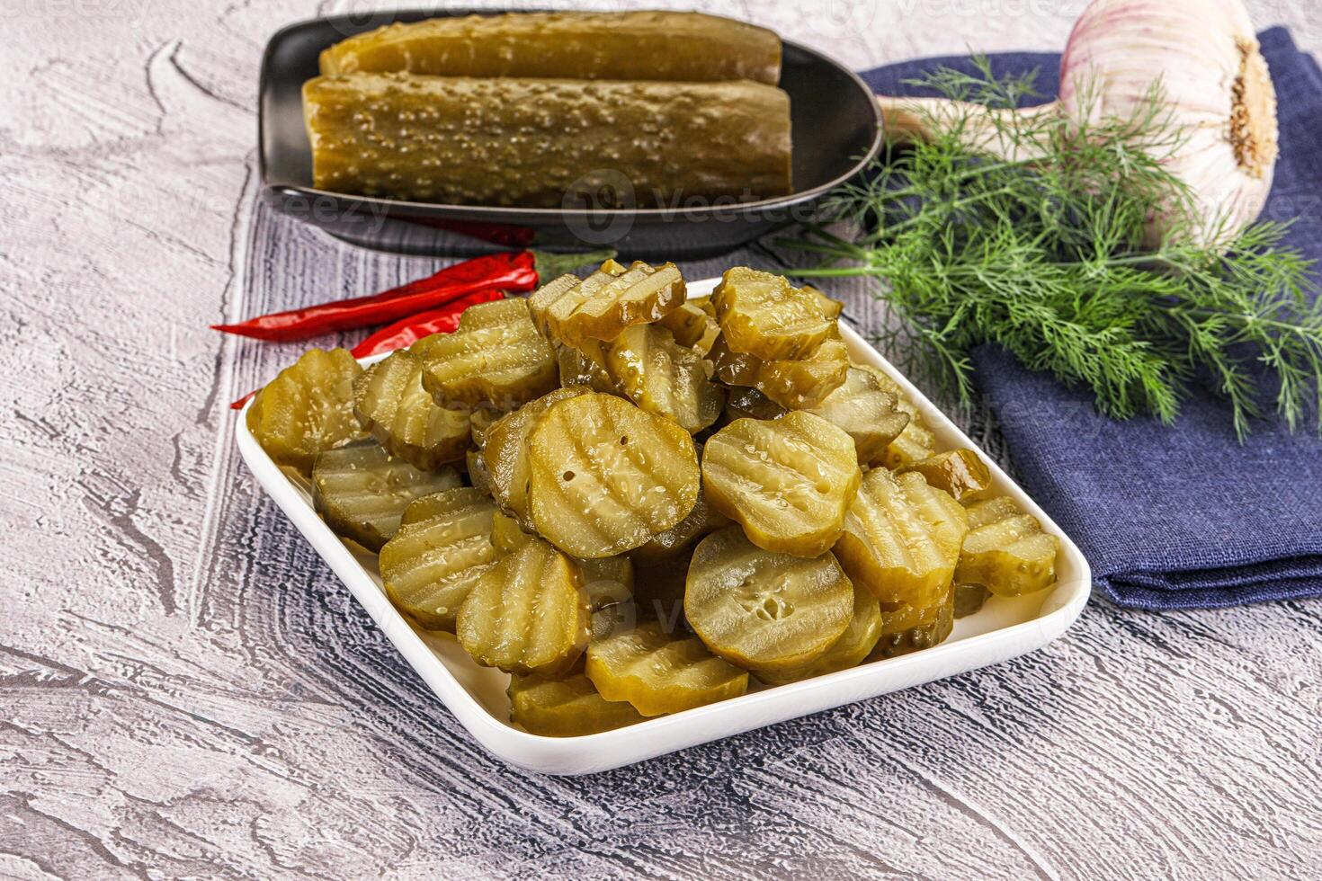 A bowl of pickles and a plate with pickles photo