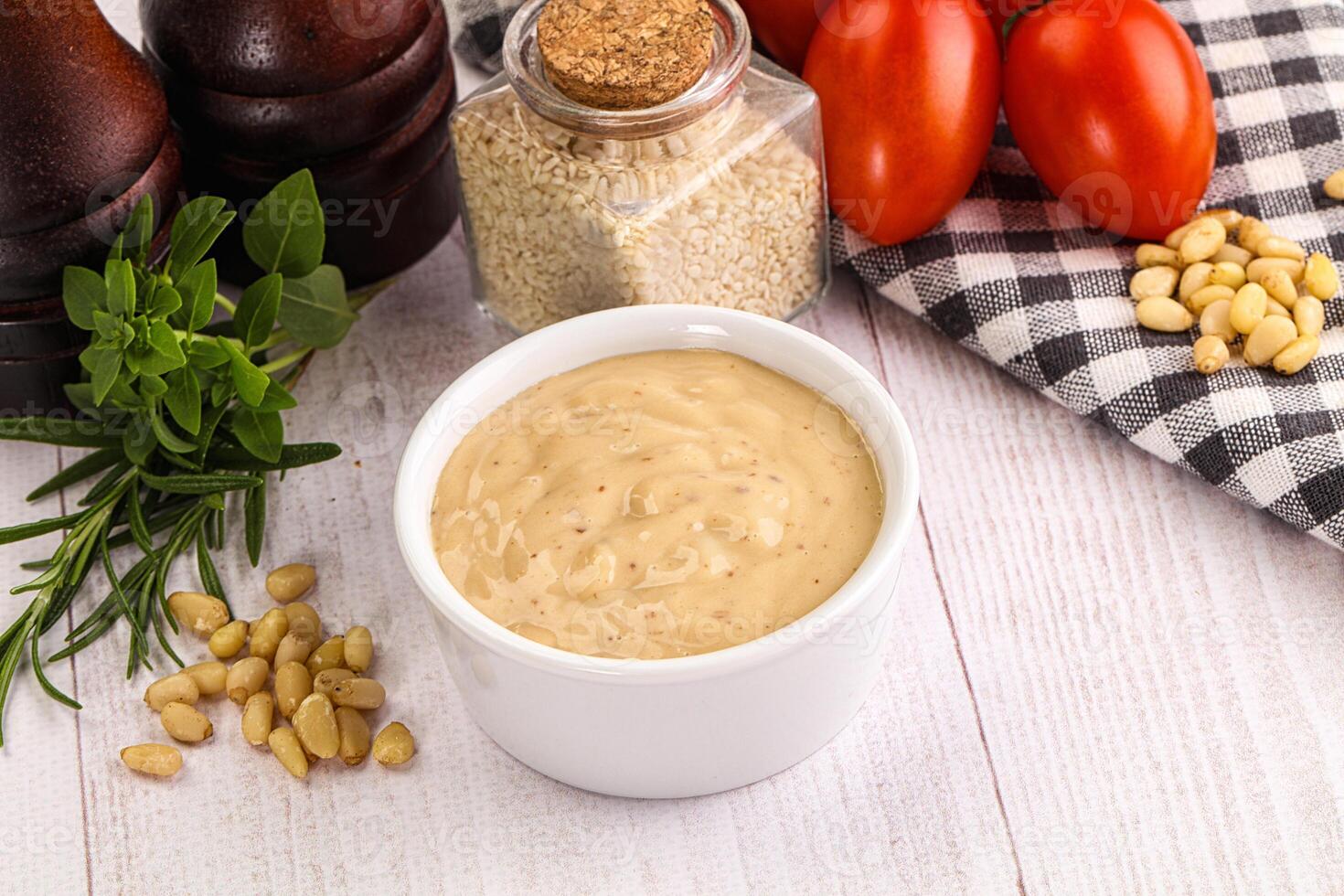 A bowl of mustard next to tomatoes, garlic and other ingredients photo