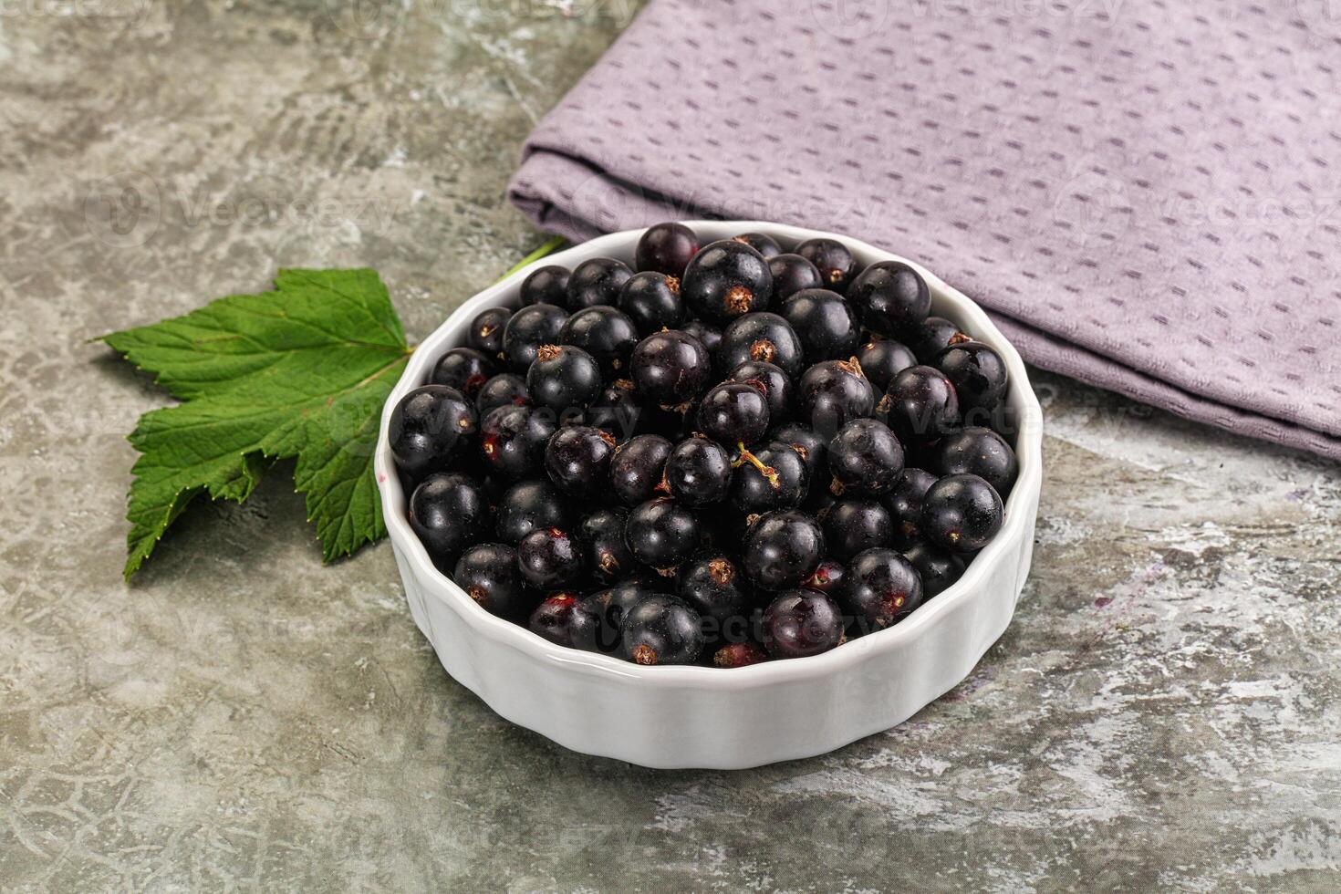 Black currant in a bowl on a gray background photo