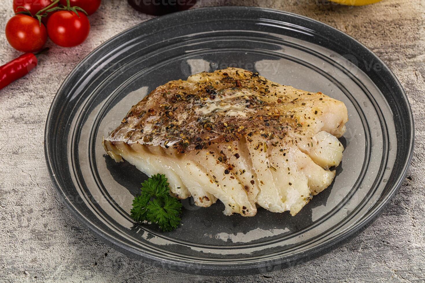 A piece of fish on a plate with some herbs photo