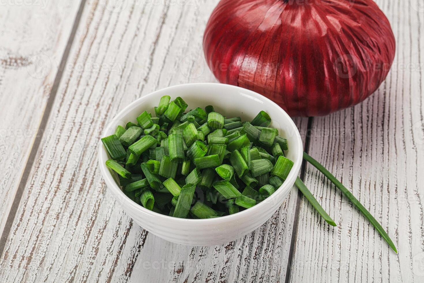 A bowl of chopped green onions and a red onion photo