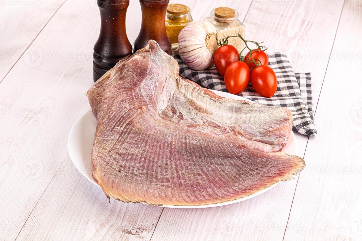 Raw fish on a plate with spices and tomatoes photo