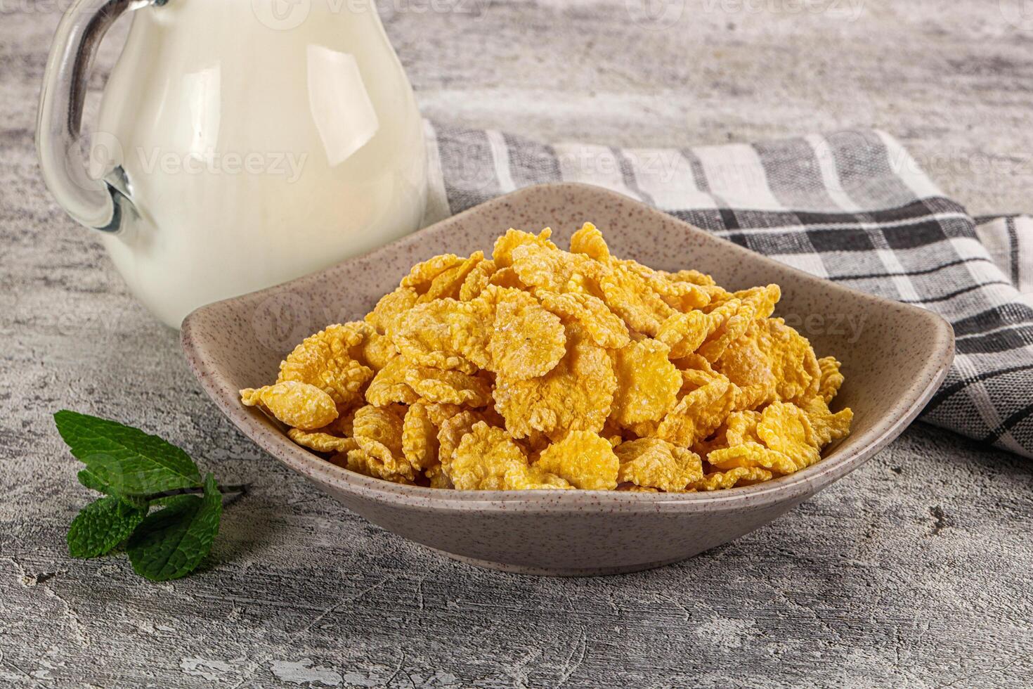 Corn flakes cereal in a bowl and a glass of milk on a wooden table photo