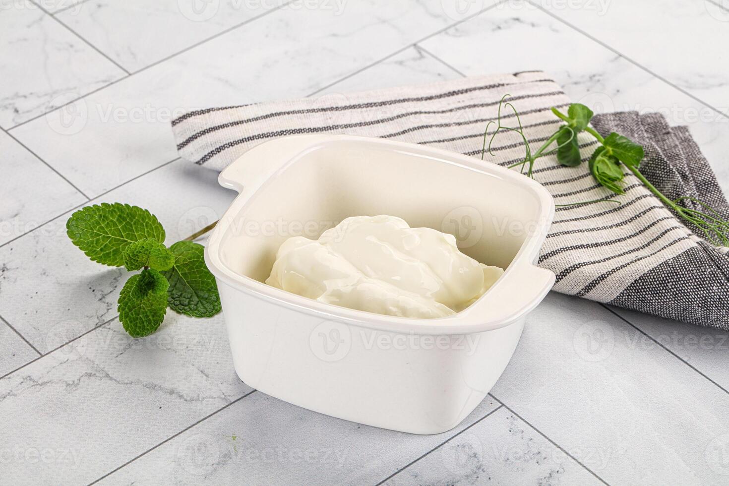 A bowl of yogurt sits on a counter next to a towel photo