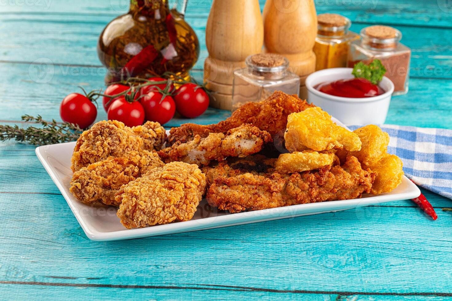 A plate of fried chicken and other food on a blue table photo