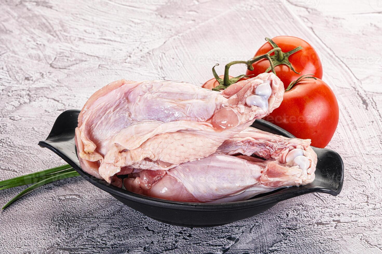 Raw chicken in a black bowl with tomatoes photo