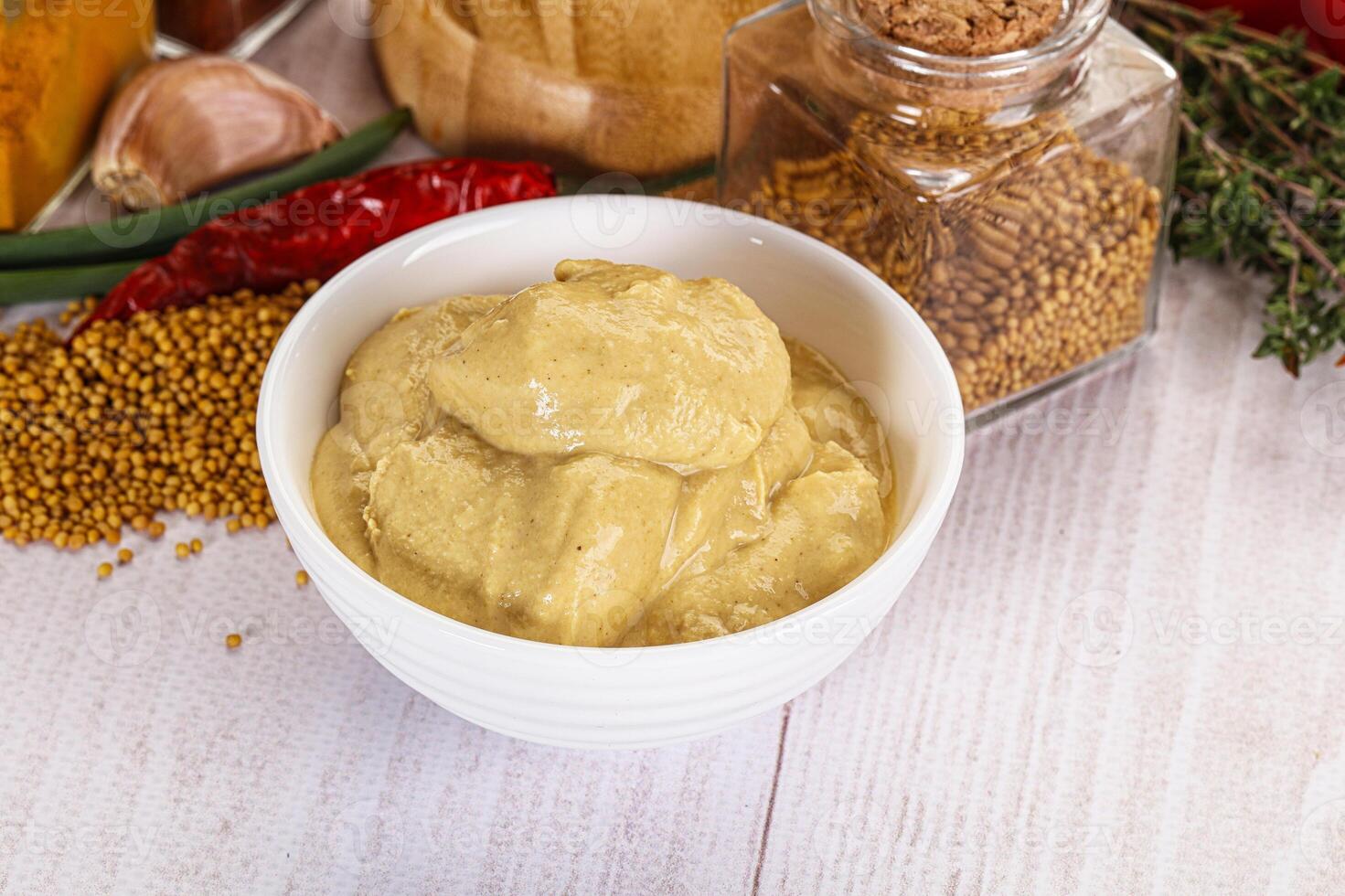 A bowl of mustard next to a bowl of spices photo