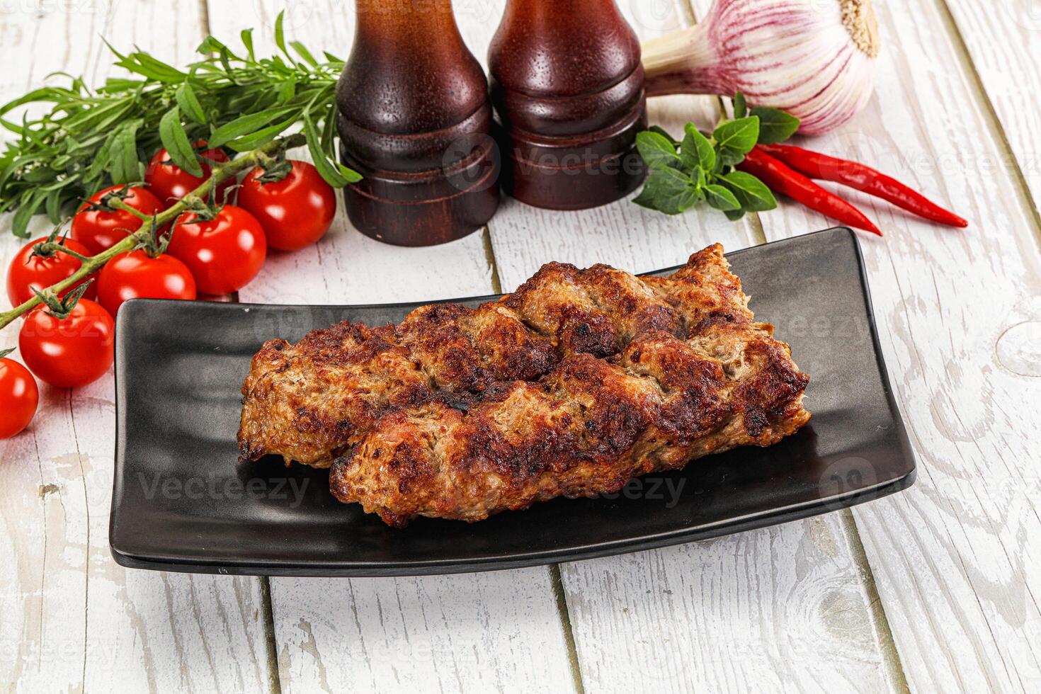 A plate with two meat skewers and a bottle of ketchup photo