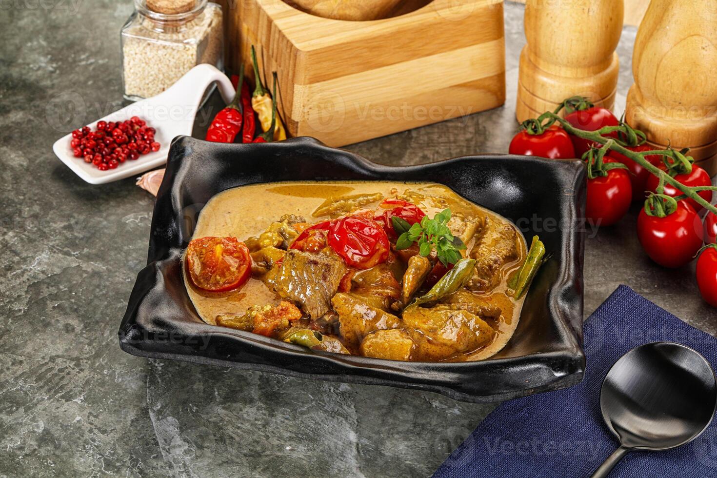 A bowl of curry with vegetables and spices on a table photo